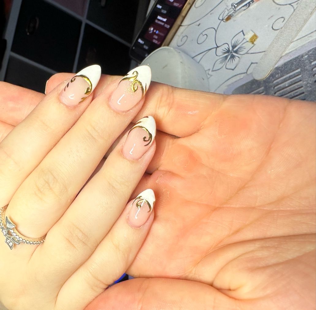 Almond nails with white French tips and gold swirl detail